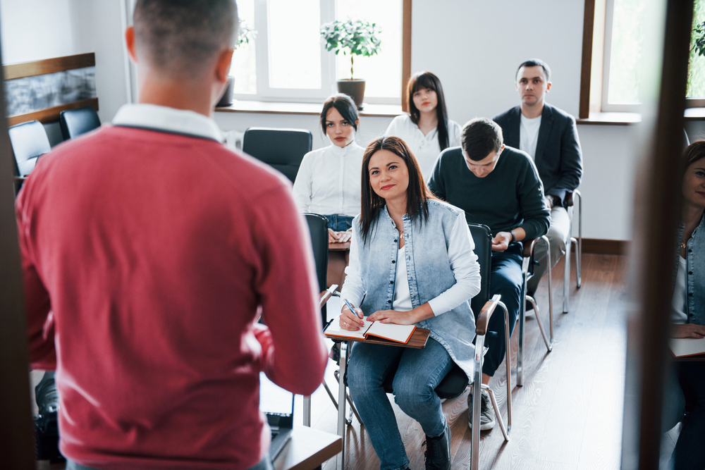 In red shirt. Group of people at business conference in modern classroom at daytime.